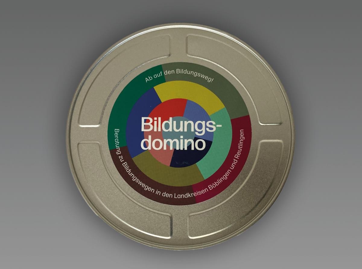Ansicht des Bildungsdominos: silberne runde Box vor grauem Hintergrund