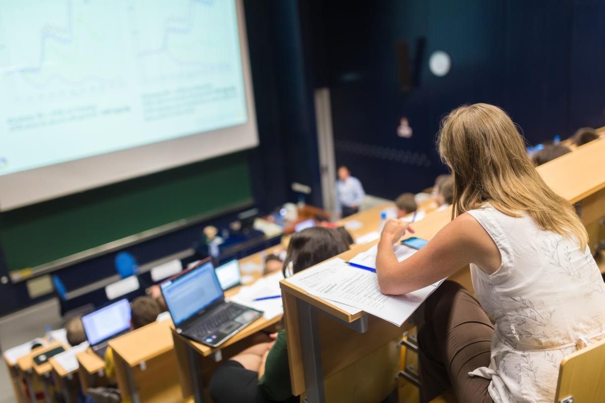 Studierende sitzen in einem Vorlesungssaal und verfolgen die Vorlesung