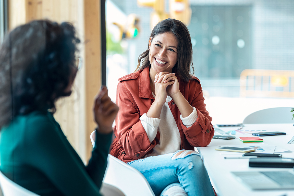 Zwei Frauen im Gespräch miteinander in einem Sitzungsraum