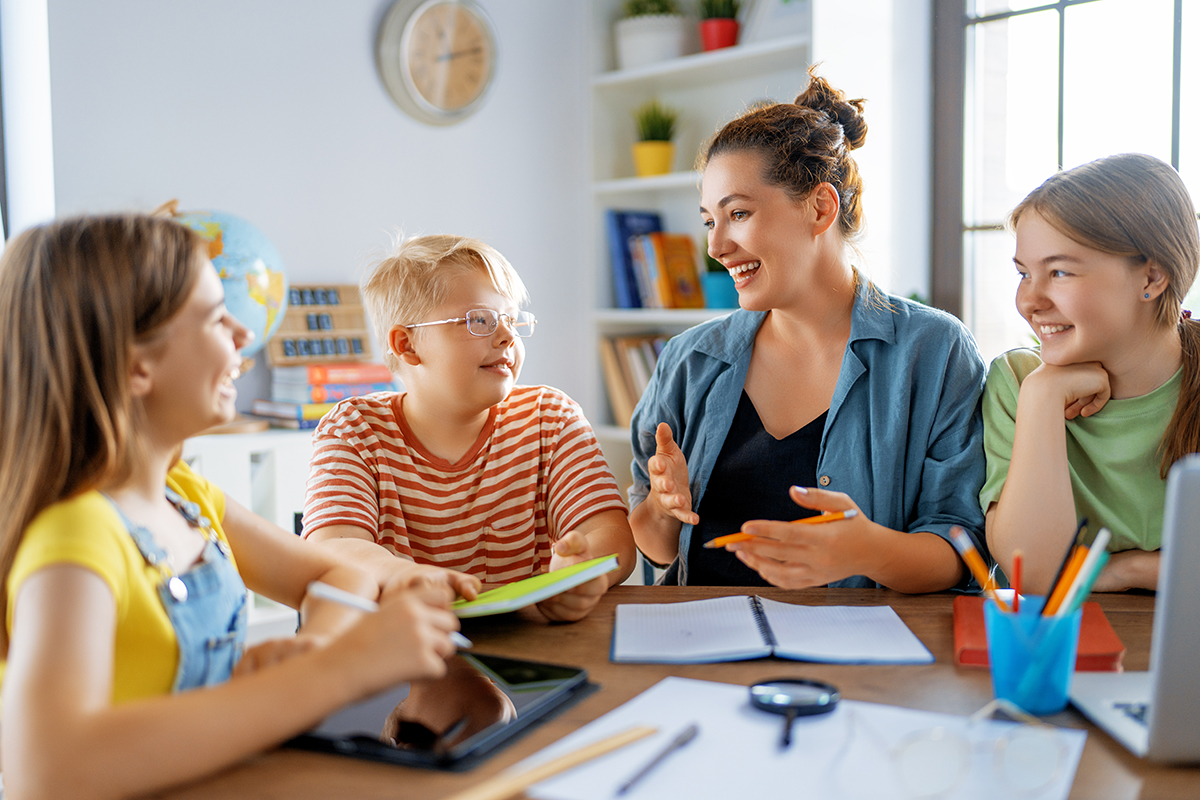 Frau mit Kindern an einem Tisch, lernend