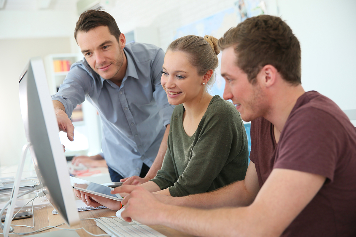 Junge Erwachsene sitzen an einem Bildschirm und recherchieren