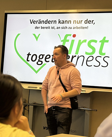 Christopf Rickels steht in einem Klassenzimmer vor einer digitalen Tafel