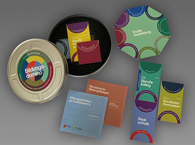 Offene Box des Bildungsdominos mit Karten und Flyern