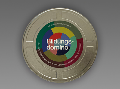 silberne Box des Bildungsdominos mit einzelnen Karten